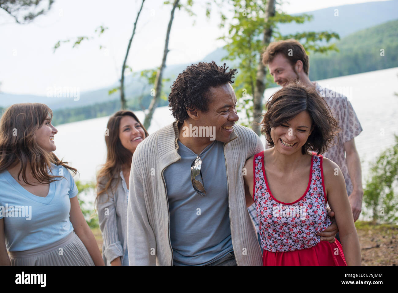 A group of people enjoying a leisurely walk by a lake. Stock Photo