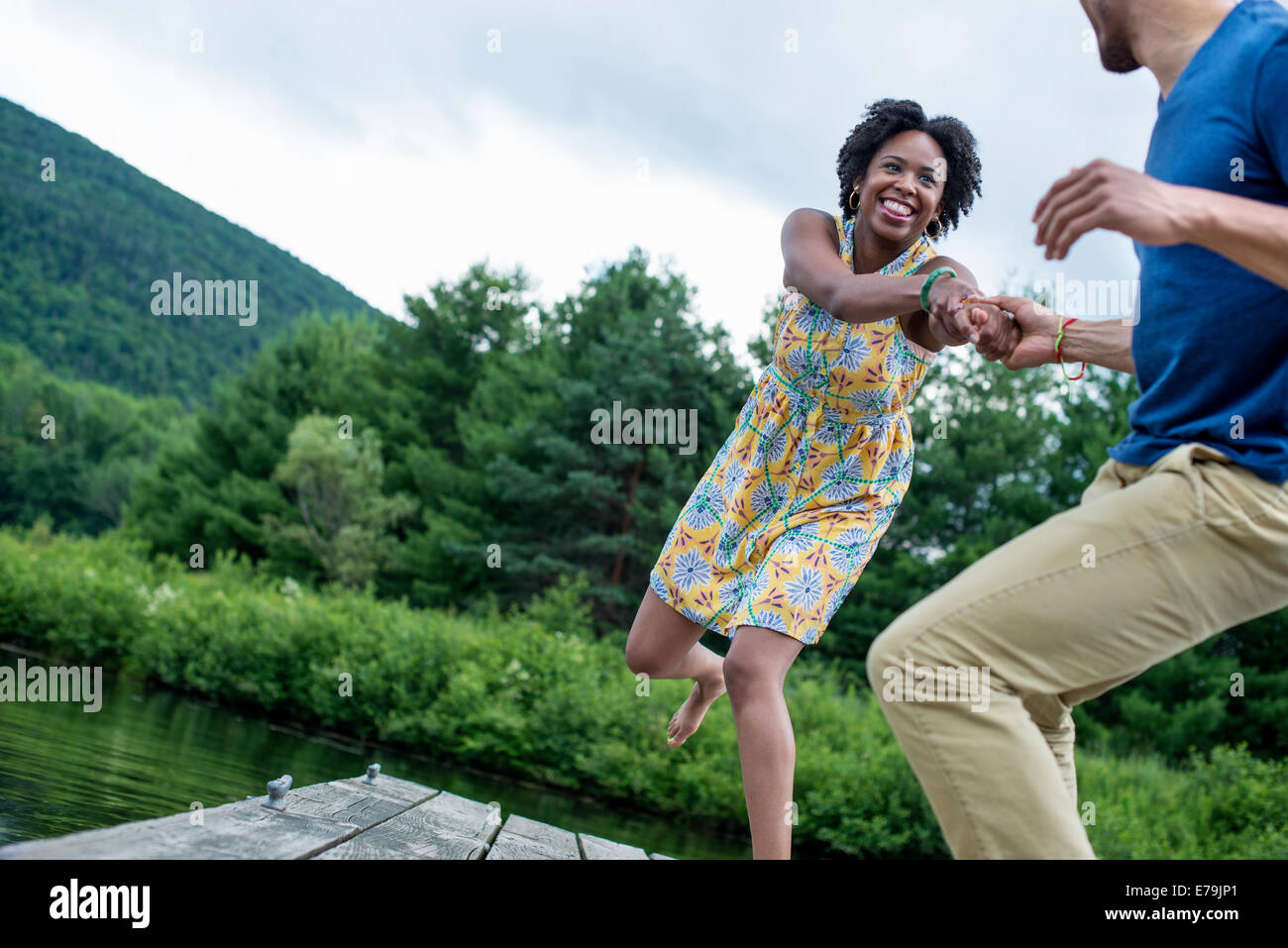 A couple trying to pull each other into the water off a jetty Stock Photo