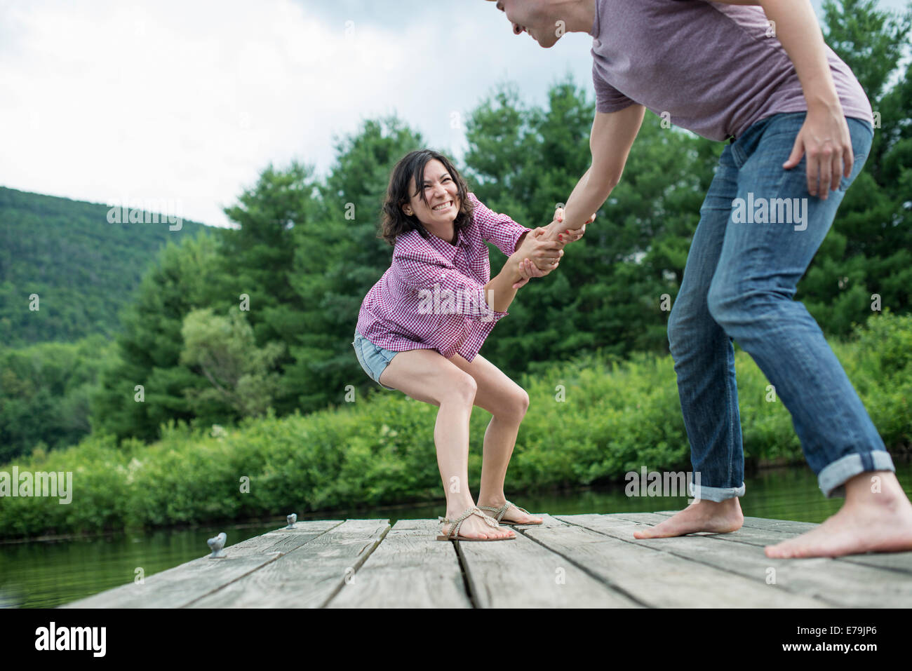 A couple trying to pull each other into the water off a jetty Stock Photo