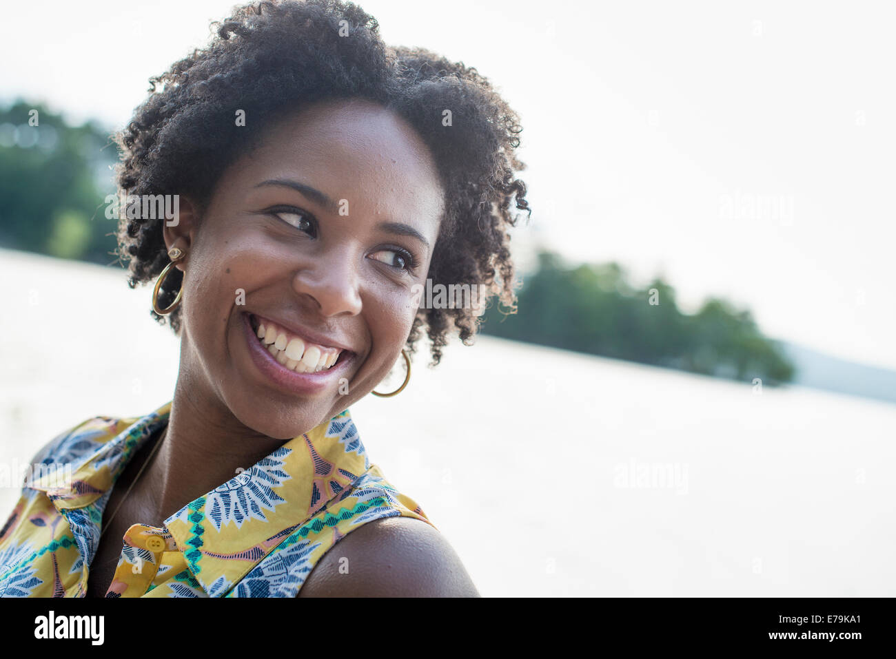 A woman smiling and laughing on a lake shore. Stock Photo