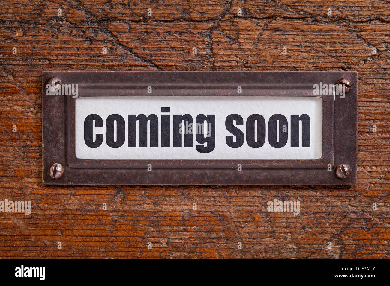coming soon  - file cabinet label, bronze holder against grunge and scratched wood Stock Photo