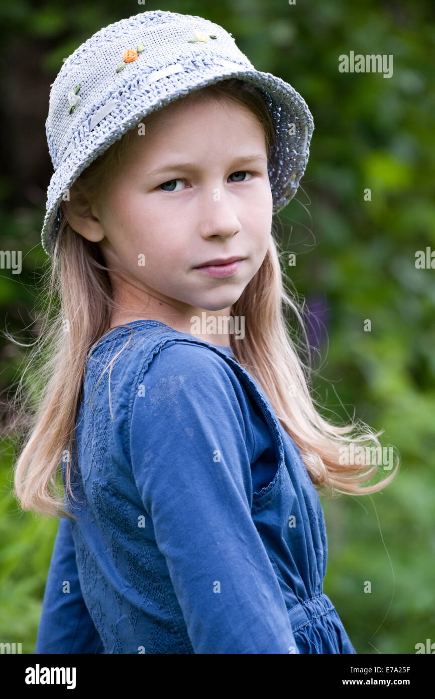 little caucasian girl portrait in blue hat on outdoor nature background