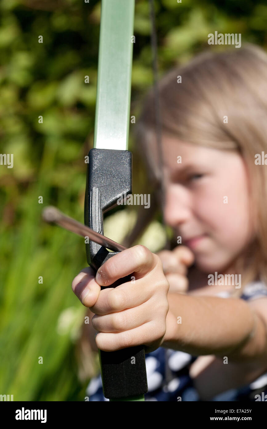 little girl aiming arrow from big bow, focus on hand Stock Photo
