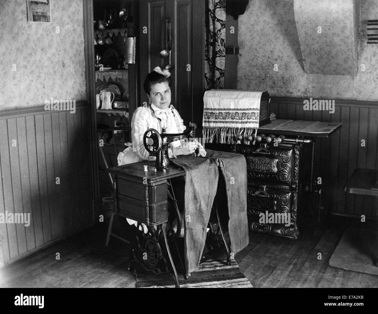 Woman Sewing Pants on Sewing Machine, circa 1905 Stock Photo
