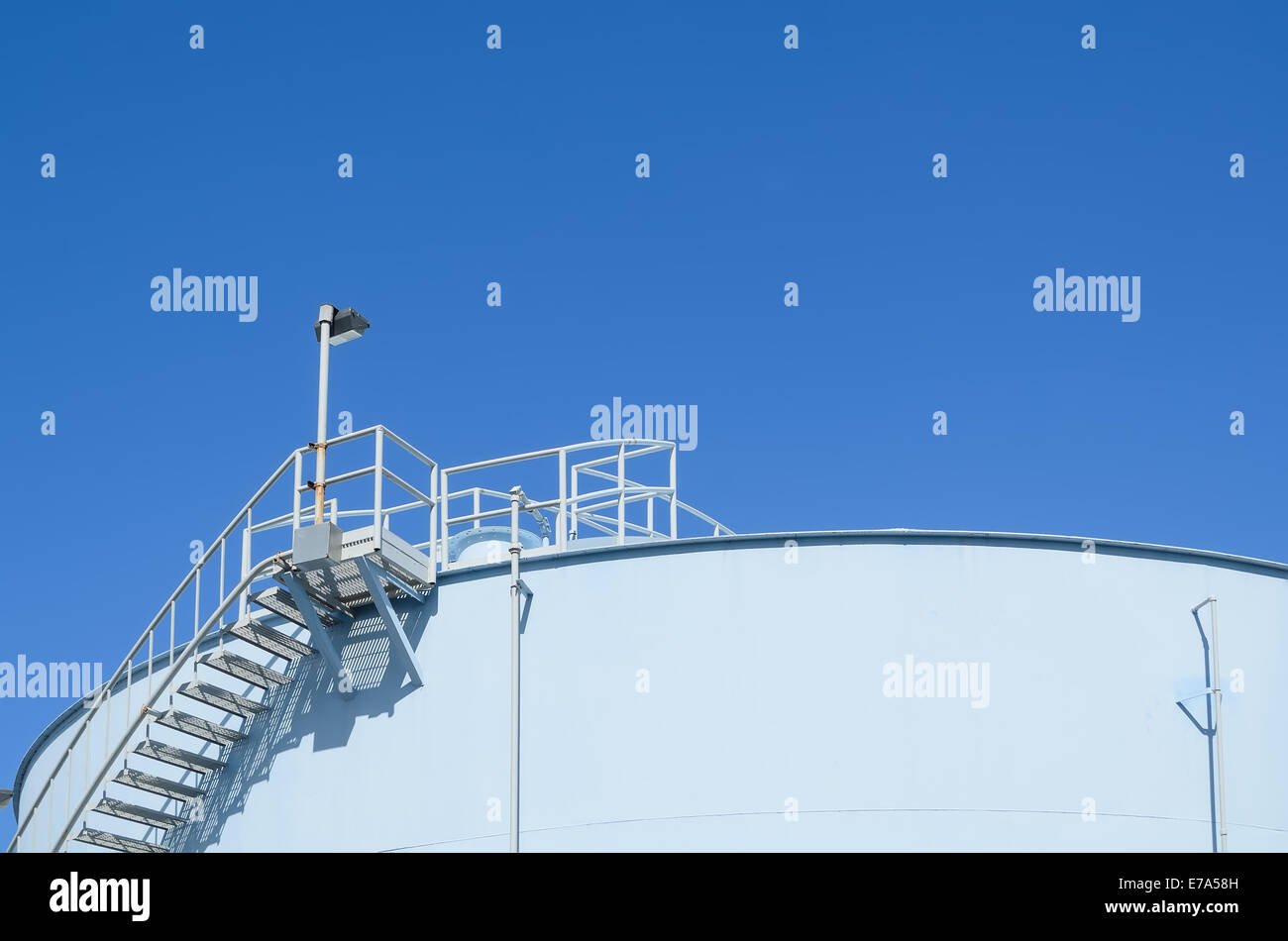 Blue industrial storage tank against cloudless blue sky Stock Photo