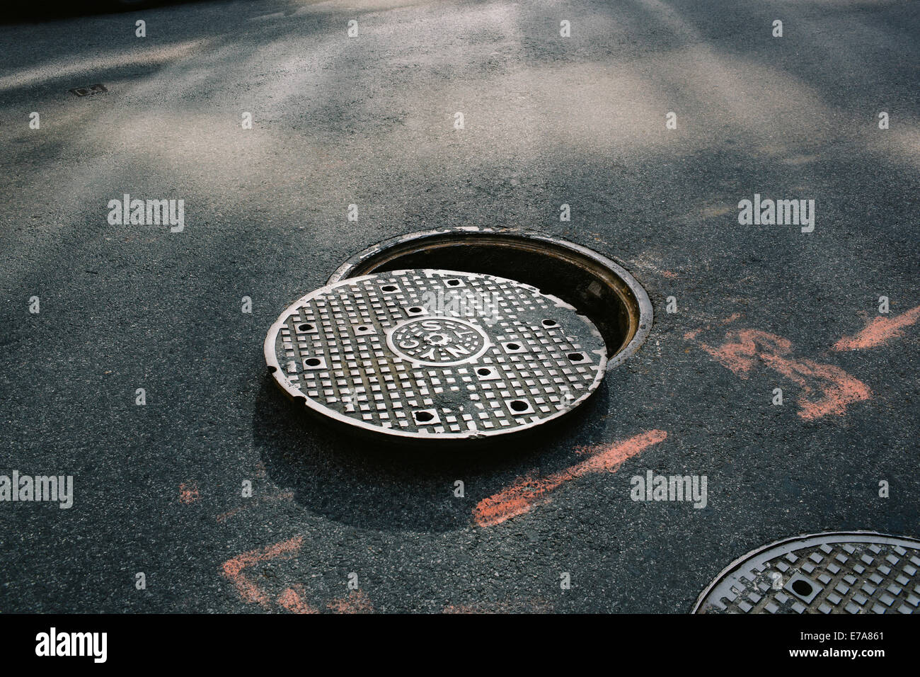 A manhole cover partially removed, close-up Stock Photo