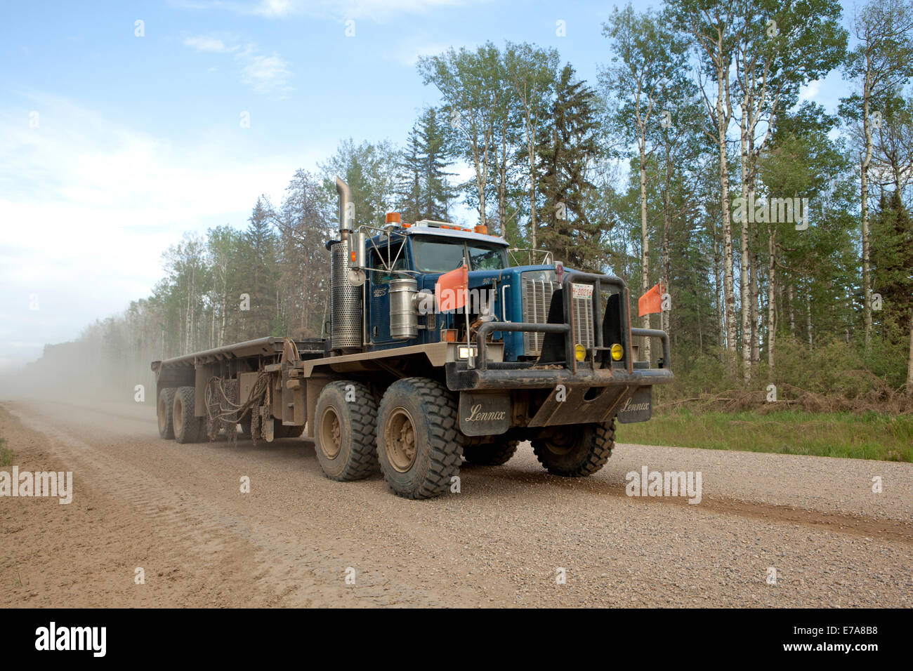 Haulage truck on dusty gravelled road by forest, Peace River, Alberta, Canada Stock Photo
