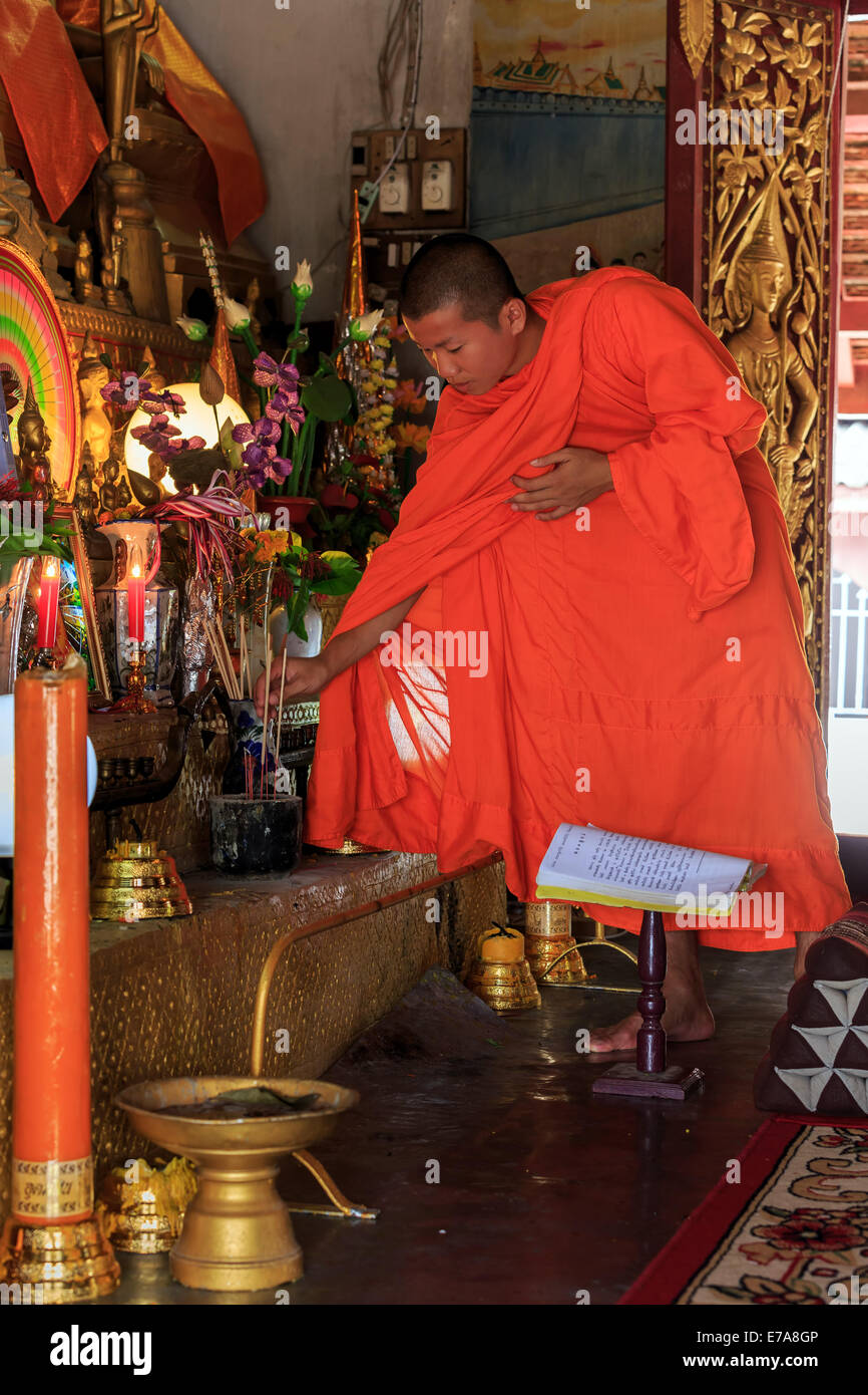 Young Buddhist Monk puts incense sticks in Laos temple Stock Photo - Alamy