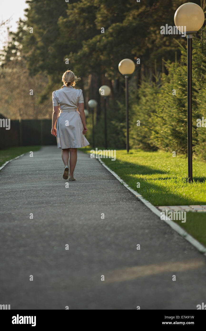 Full length rear view of woman walking on footpath Stock Photo