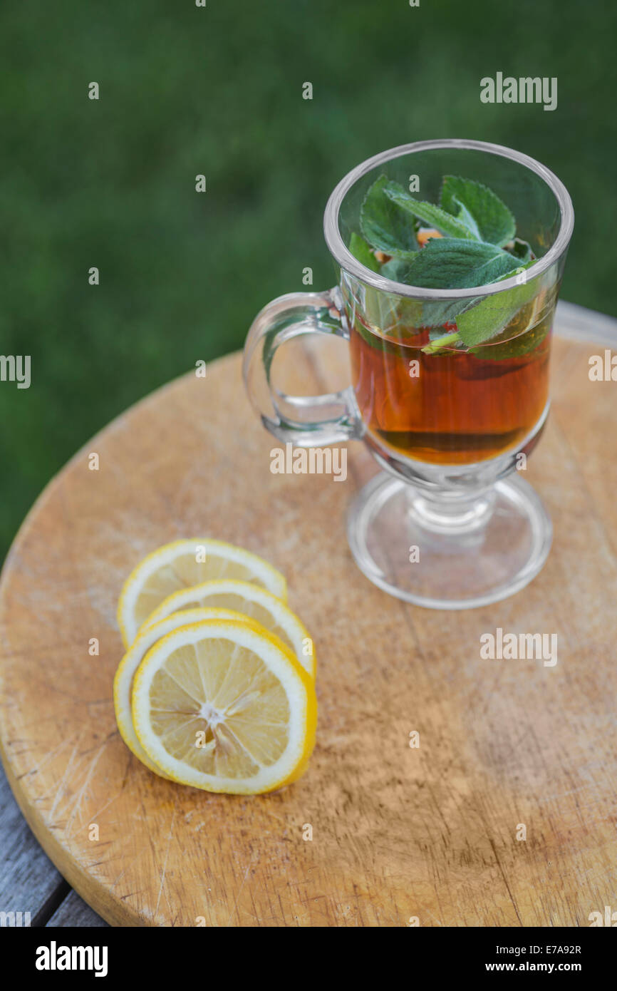 Iced tea with mint by lime slices on outdoor table Stock Photo