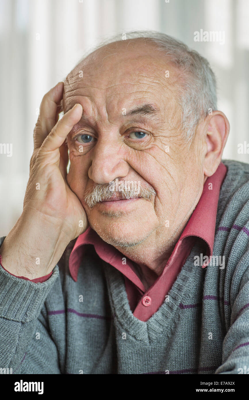 Portrait of worried senior man with hand on face at home Stock Photo