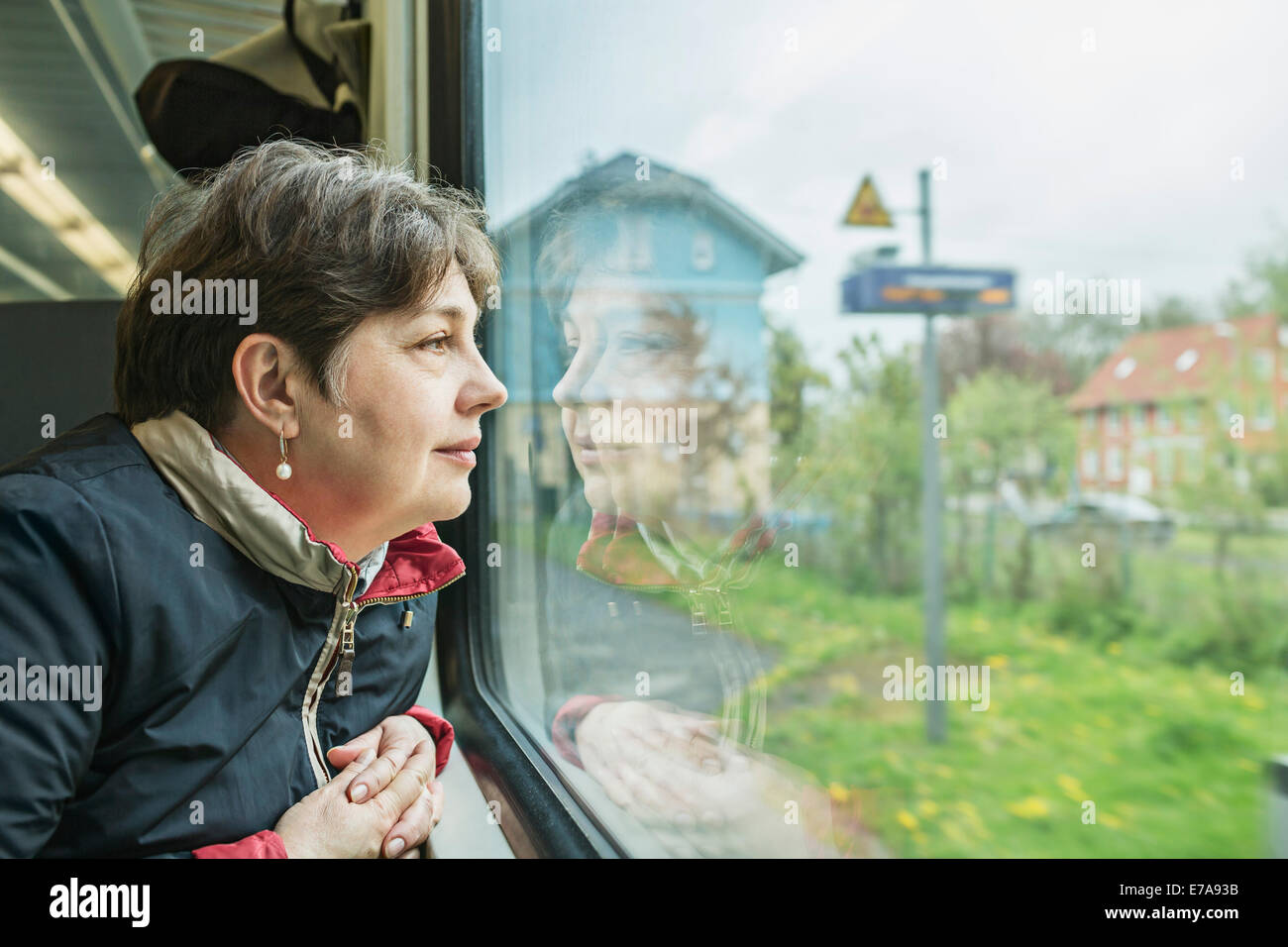 Mature woman looking through train window Stock Photo