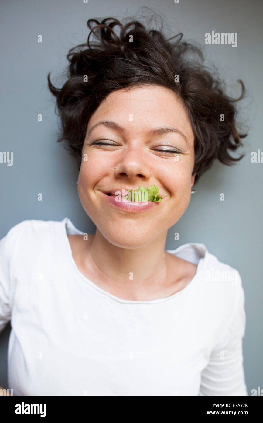A woman eating lettuce over grey background Stock Photo