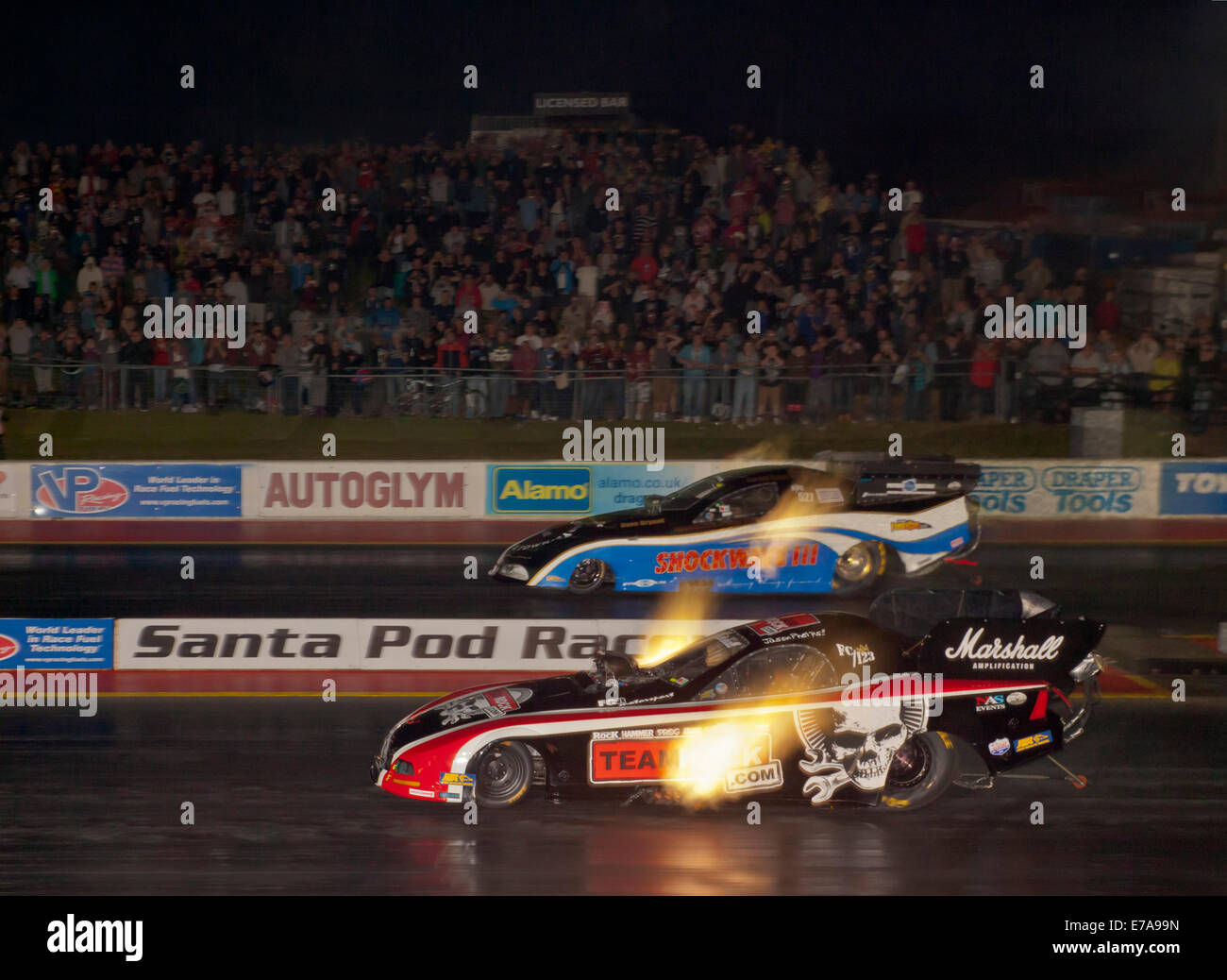Top Fuel Funny car dragsters racing at night. Gordon Smith driving a Dodge Stratus far side, Jason Phelps Ford Mustang near side Stock Photo