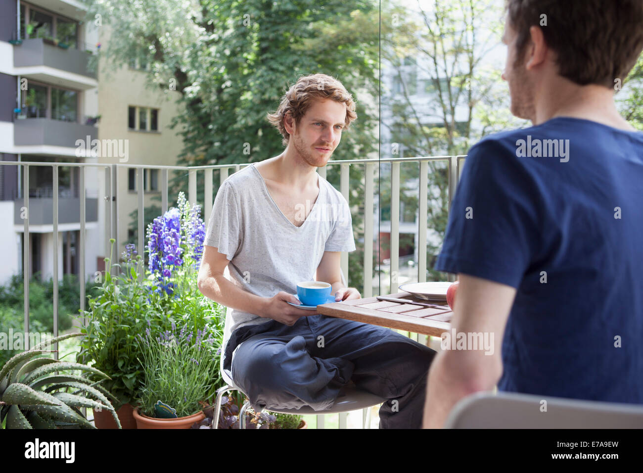 Gay man looking at partner while having coffee at porch Stock Photo