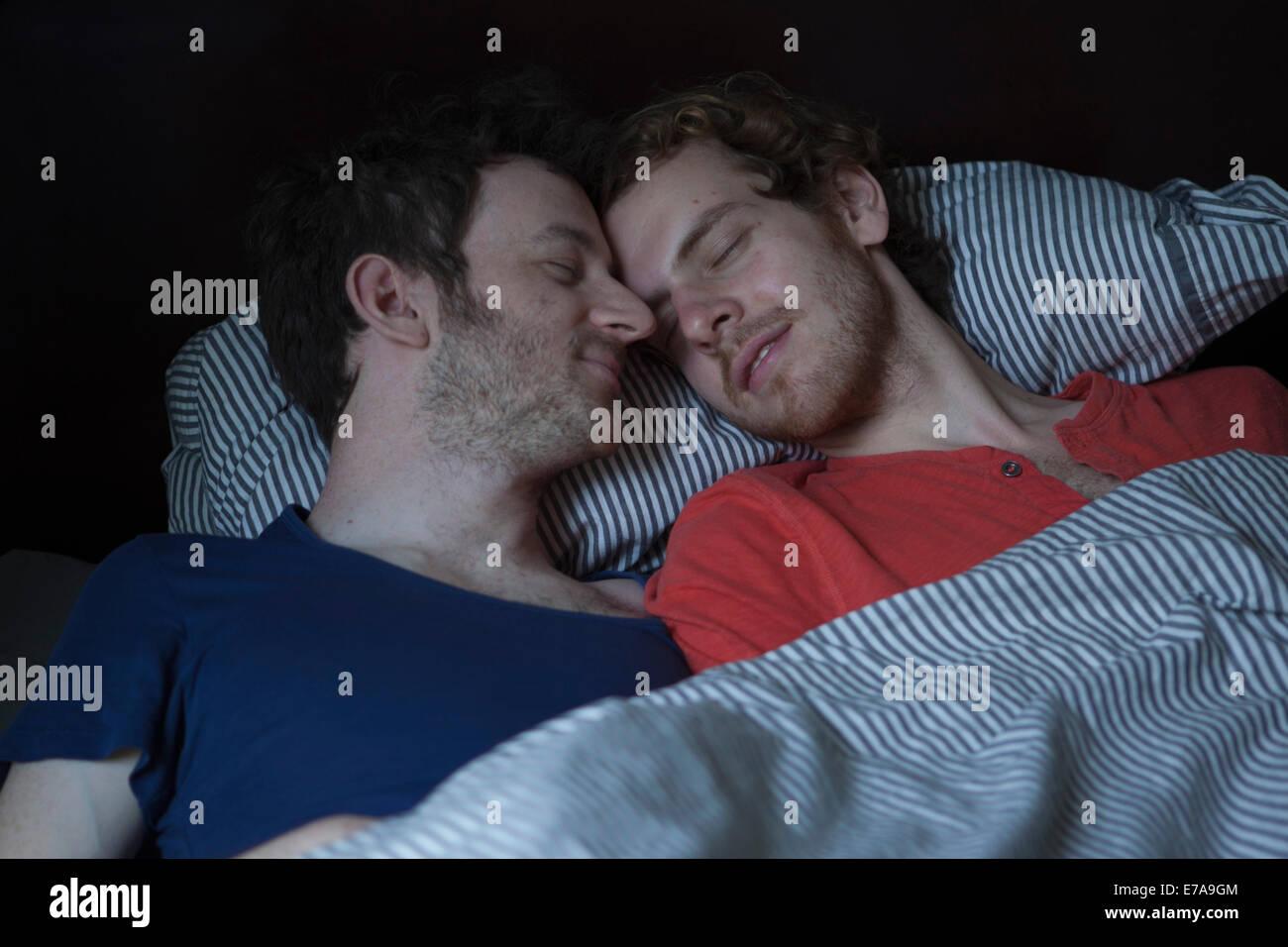 Relaxed young gay couple sleeping in bed Stock Photo