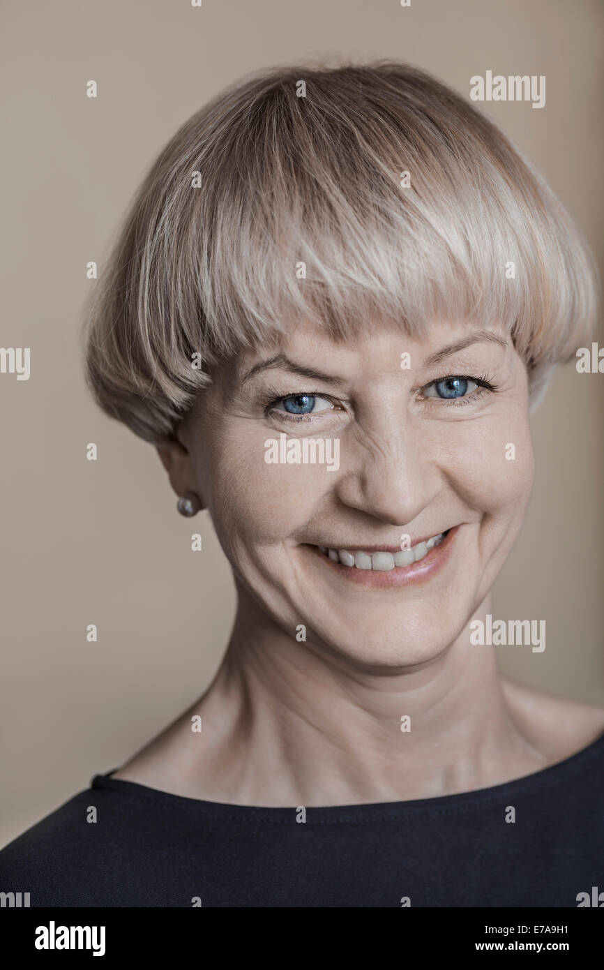 Close-up portrait of mature woman smiling against colored background Stock Photo