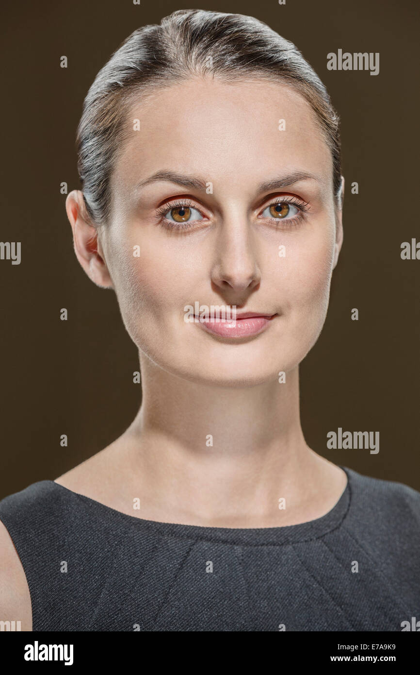 Portrait of young woman against brown background Stock Photo - Alamy