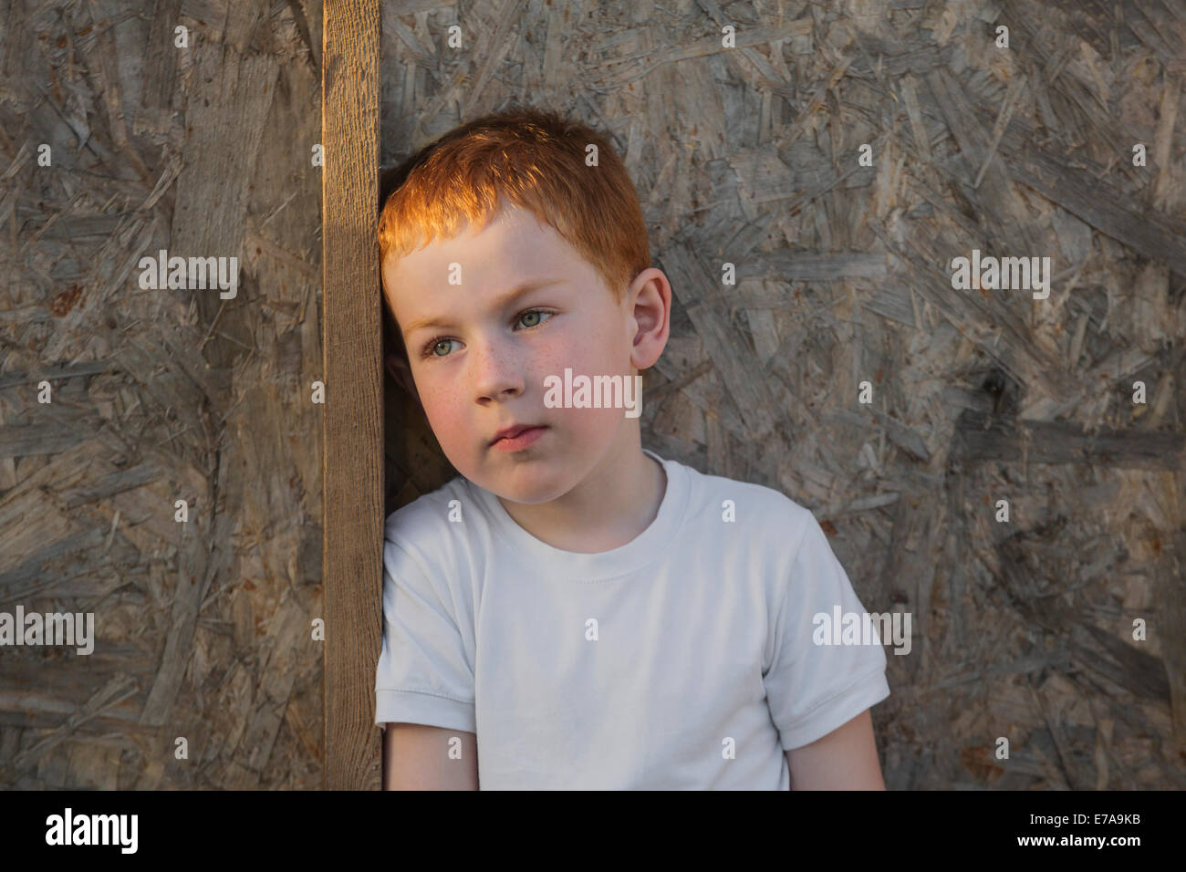 Thoughtful boy looking away against wall Stock Photo