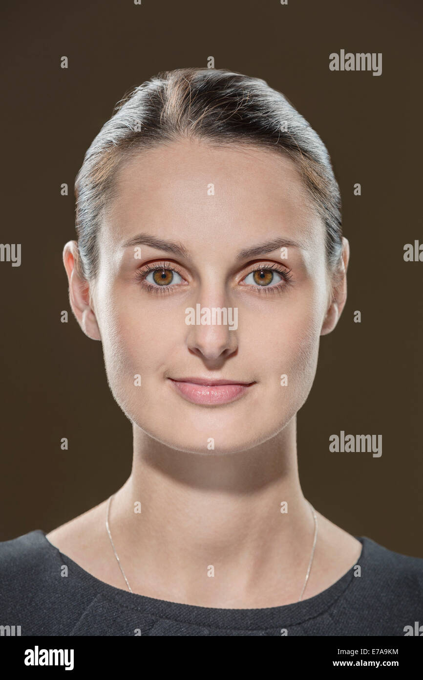 Portrait of young woman against brown background Stock Photo - Alamy