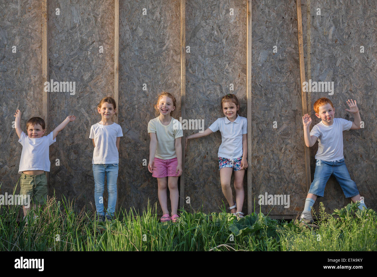 Portrait of playful children standing against wall in park Stock Photo