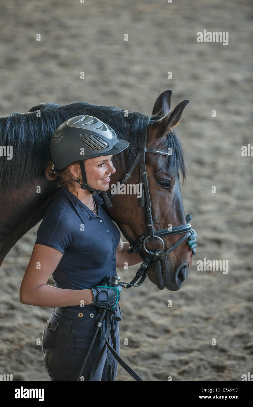 Side view of loving woman with horse at stable Stock Photo