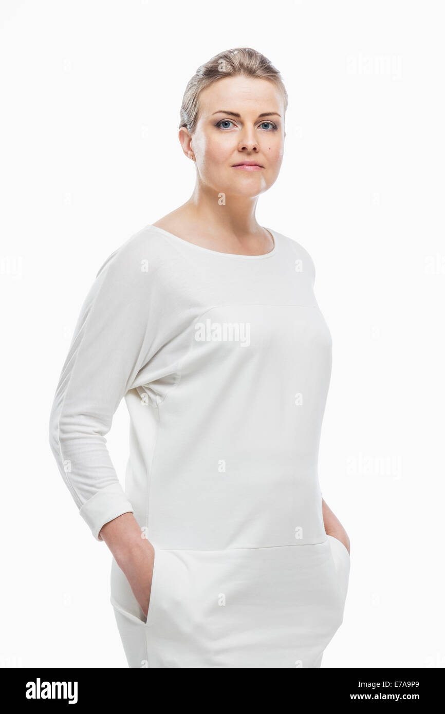 Portrait of confident woman with hands in pockets against white background Stock Photo