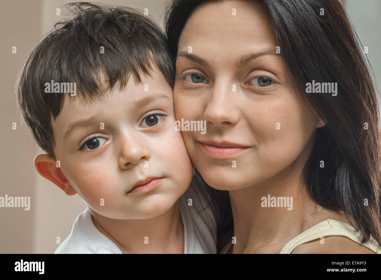 Close-up portrait of mother and son with cheek to cheek at home Stock Photo