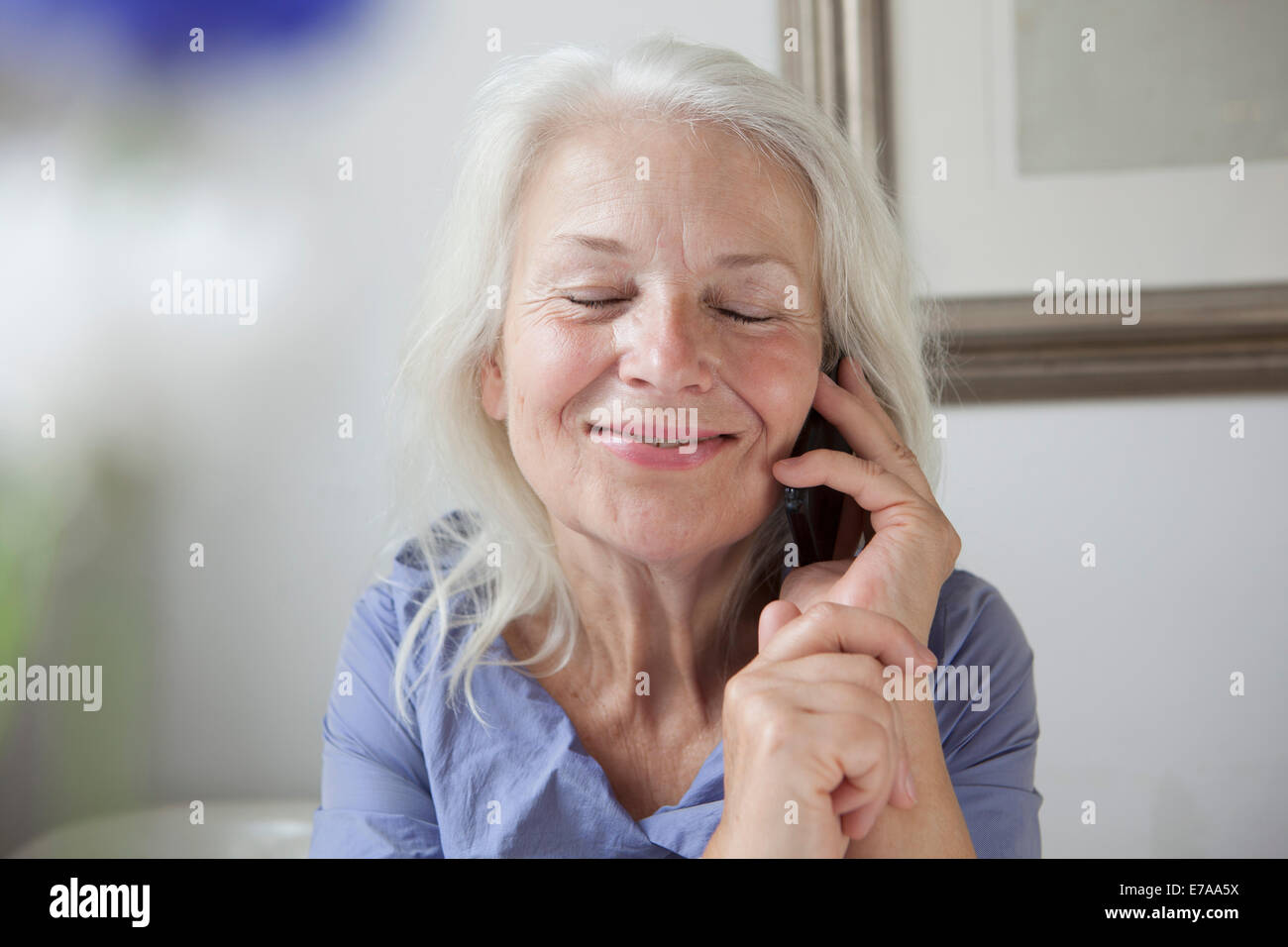Delightful senior woman answering mobile phone at home Stock Photo