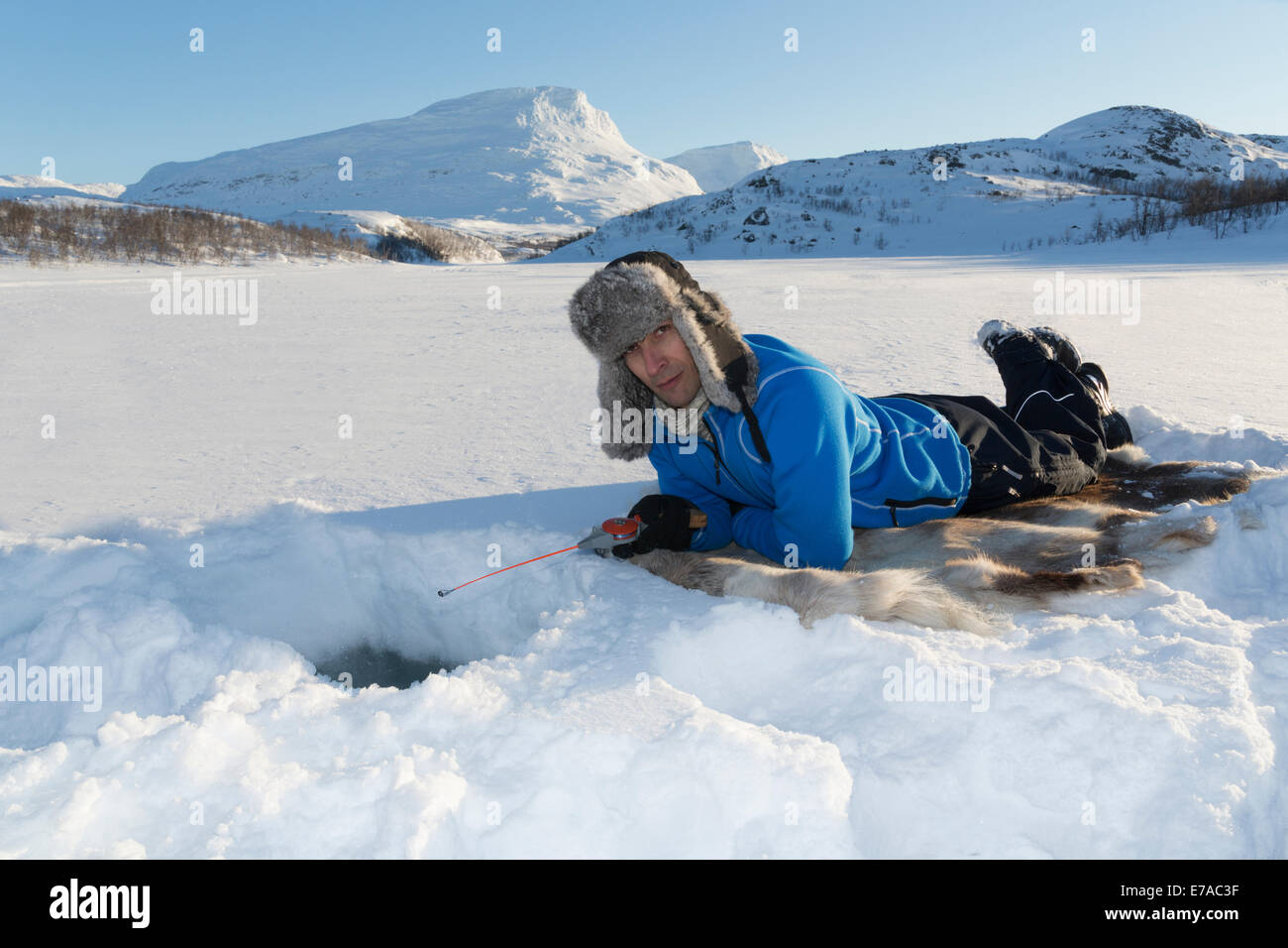 White man, 4045 years old, icefishing, lying on a reindeer fur in