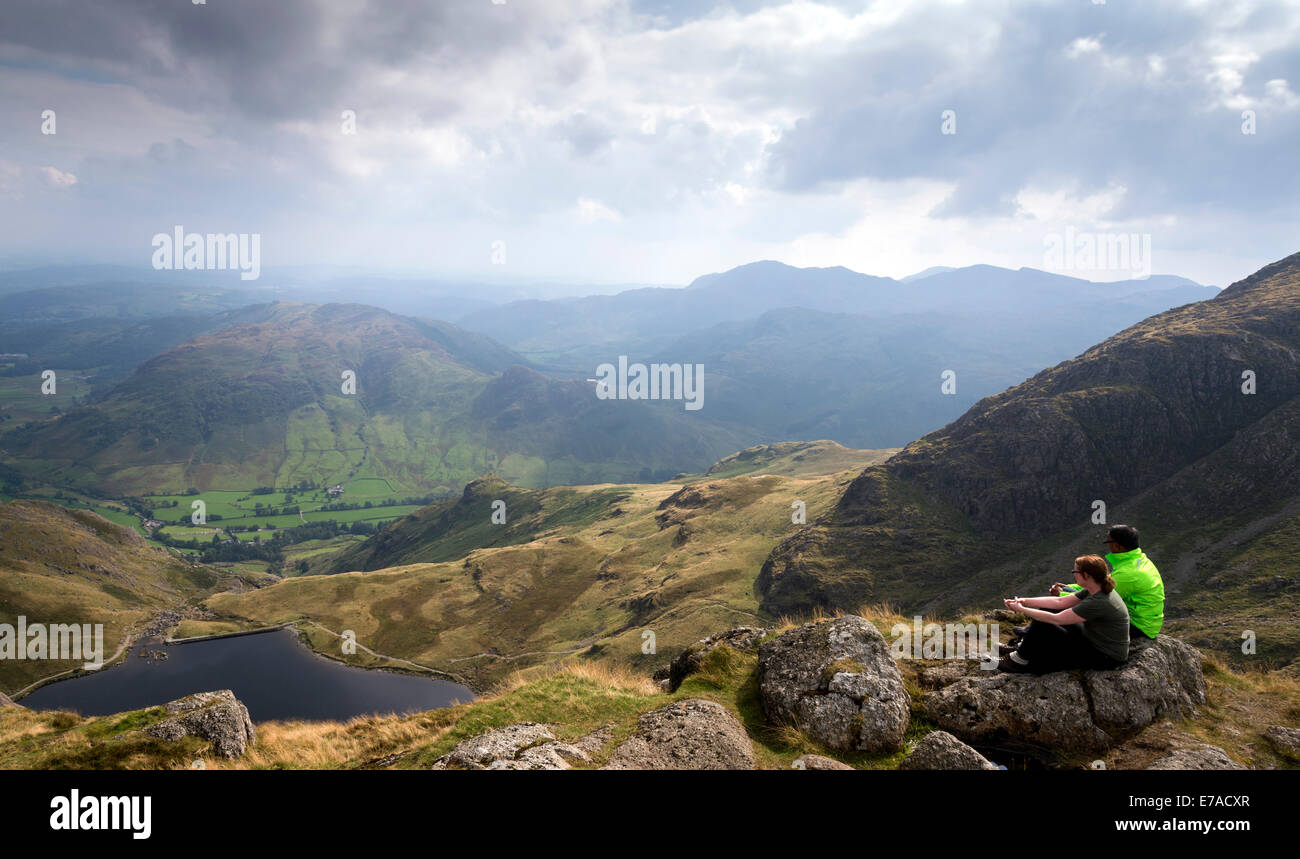 Two people sitting on the summit of Pavey Ark part of the Langdale Pikes in the Lake District Cumbria North West England UK Stock Photo