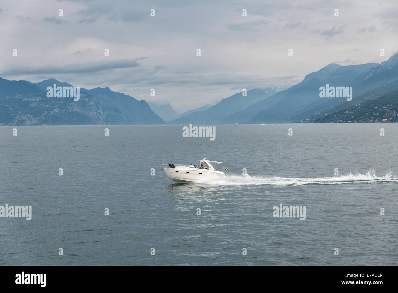 Smart little luxury motor cruiser passes across Lake Garda in Northern Italy with the mountains of the Northern part of the lake Stock Photo