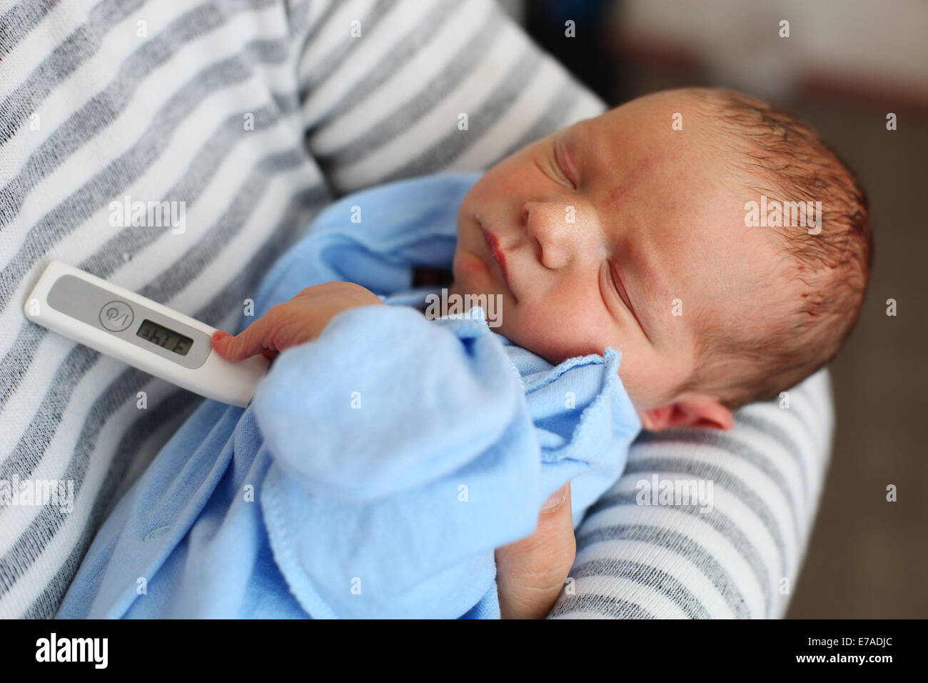 Father taking newborn son's temperature with thermometer Stock Photo