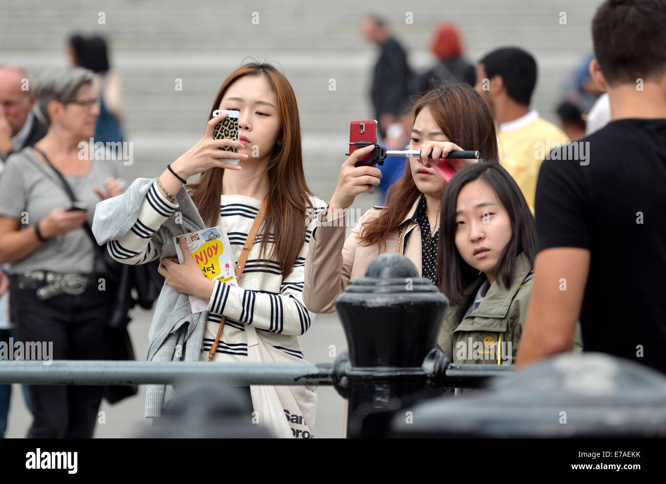 London, England, UK. Trafalgar Square: Japanese tourists taking photos with their mobile phones Stock Photo