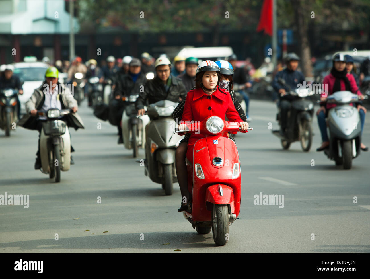 Smart young Vietnamese woman on red scooter in traffic Hanoi, Vietnam Stock Photo