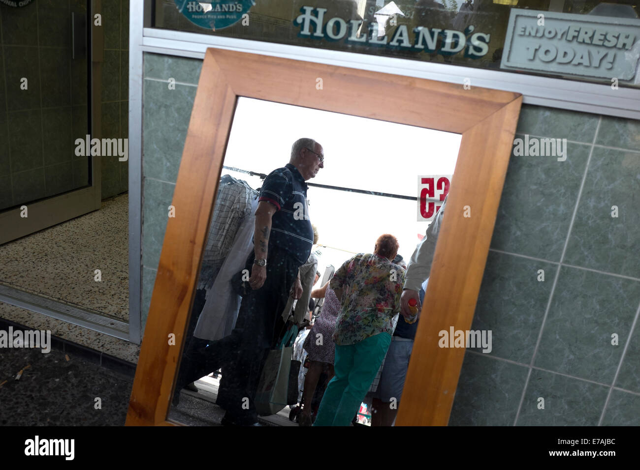 Shoppers reflected in mirror market stall selling Stock Photo Alamy
