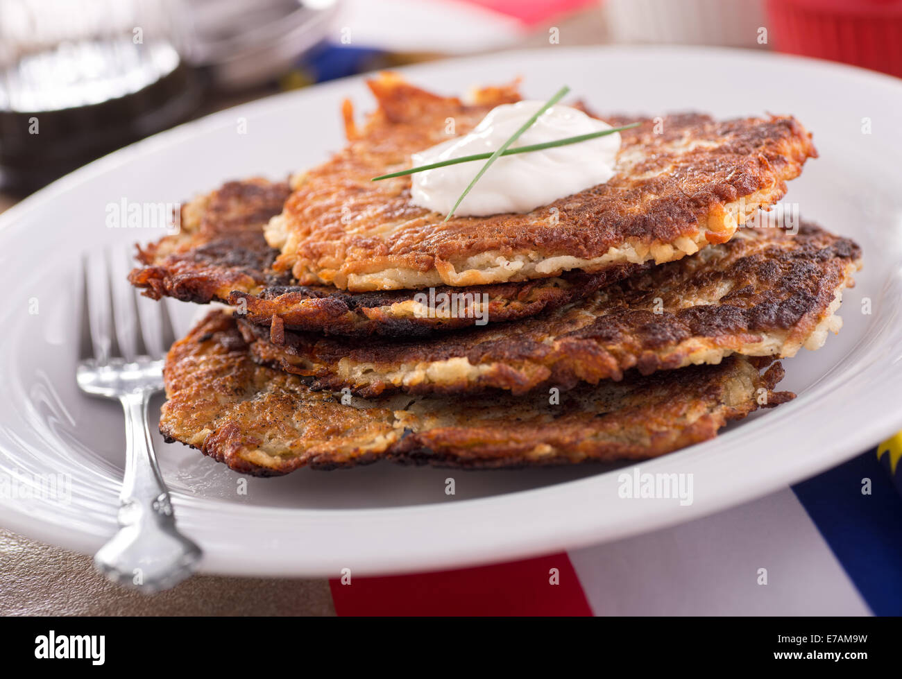 A stack of delicious homemade potato pancakes with sour cream and chives. Stock Photo