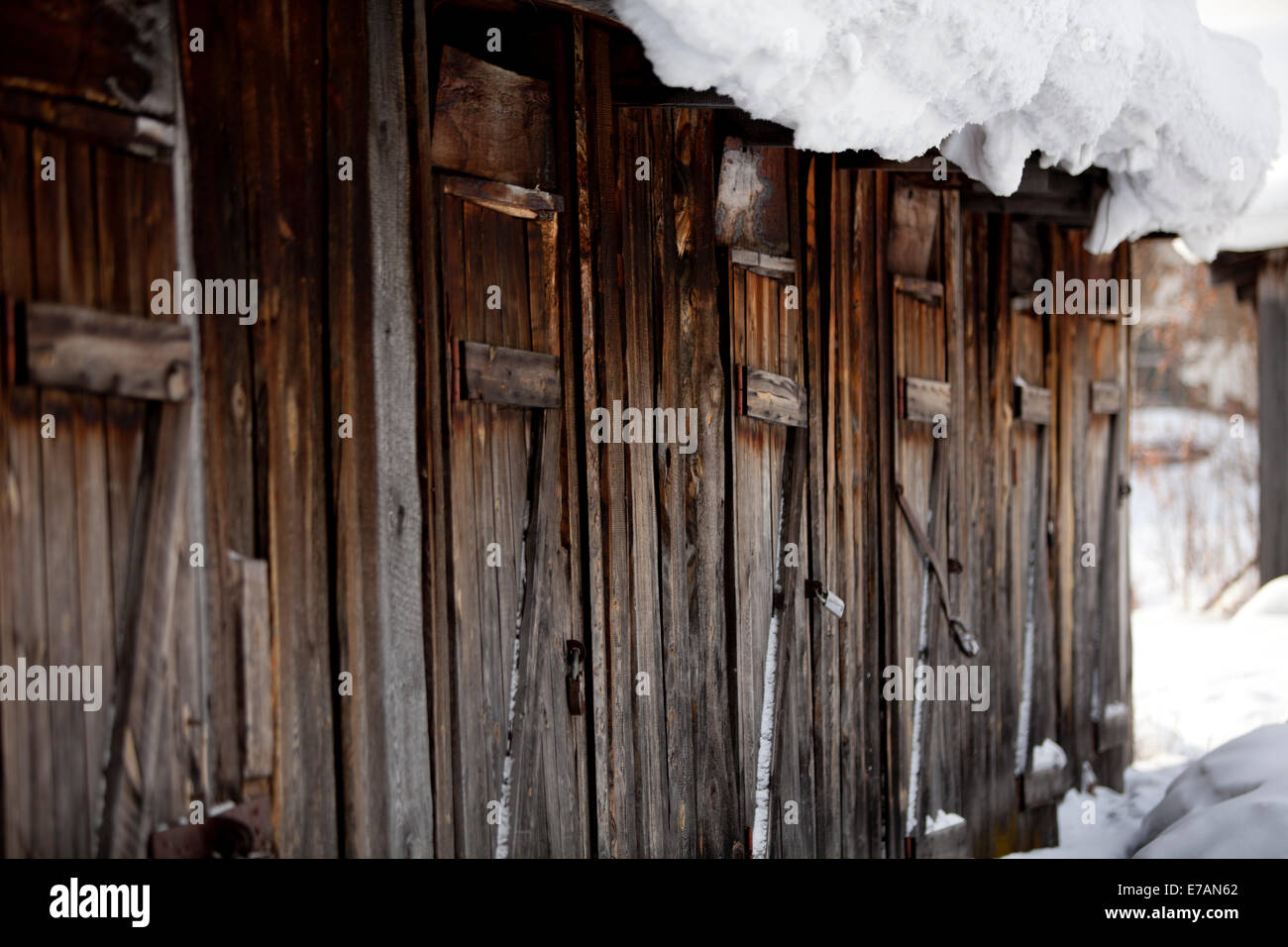 faded wooden outbuildings doors with snow Stock Photo