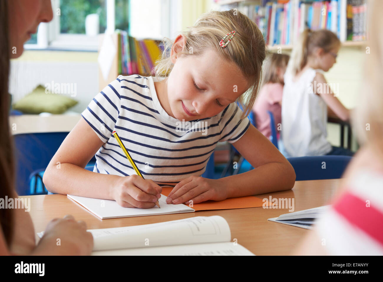 Elementary School Pupil Working At Desk In Classroom Stock Photo