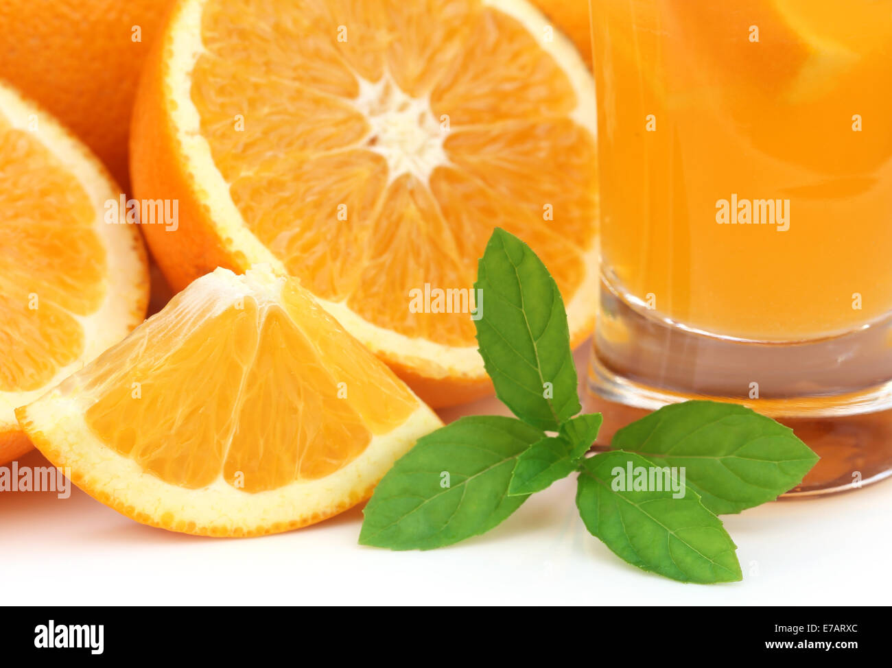 Oranges with glass of juice and green mint leaves Stock Photo
