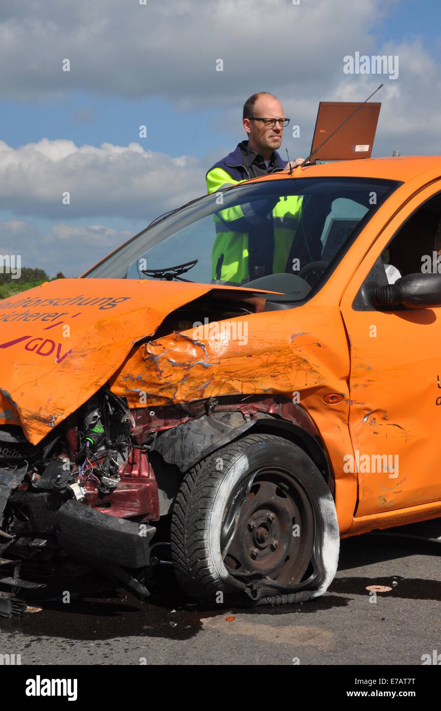 A staff member documents the damages on an orange car after it crashed