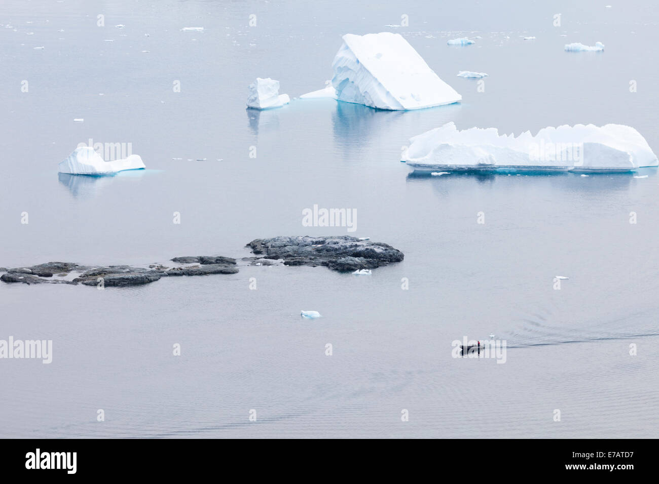 Icebergs, rocky islets and a rubber boat near Danco Island, Antarctica Stock Photo
