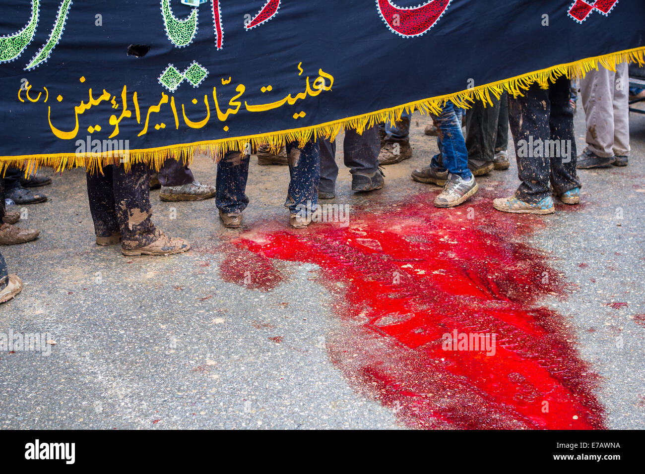 Shiite Muslim men, standing in the blood of a ritually slaughtered sheep, on Ashura Day, in Bijar, Iran. Stock Photo