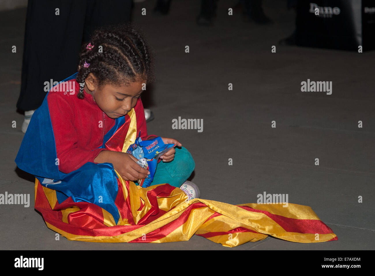 London, UK. 11 September, 2014. A child wrapped in a Catalan flag sits on the pavement eating sweets at a pro-independence rally opposite Downing Street. Credit:  Pavement Press  Pictures/Alamy Live News Stock Photo