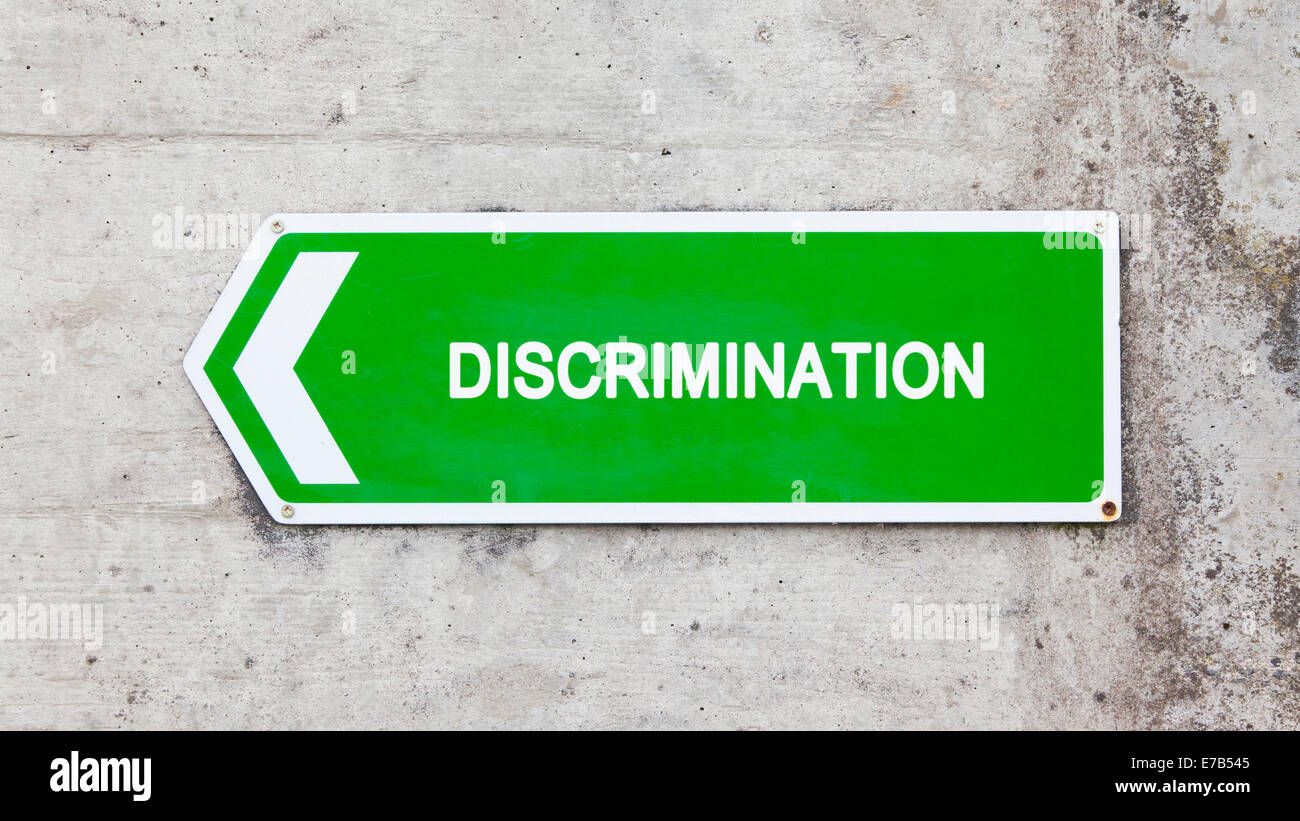 Green sign on a concrete wall - Discrimination Stock Photo