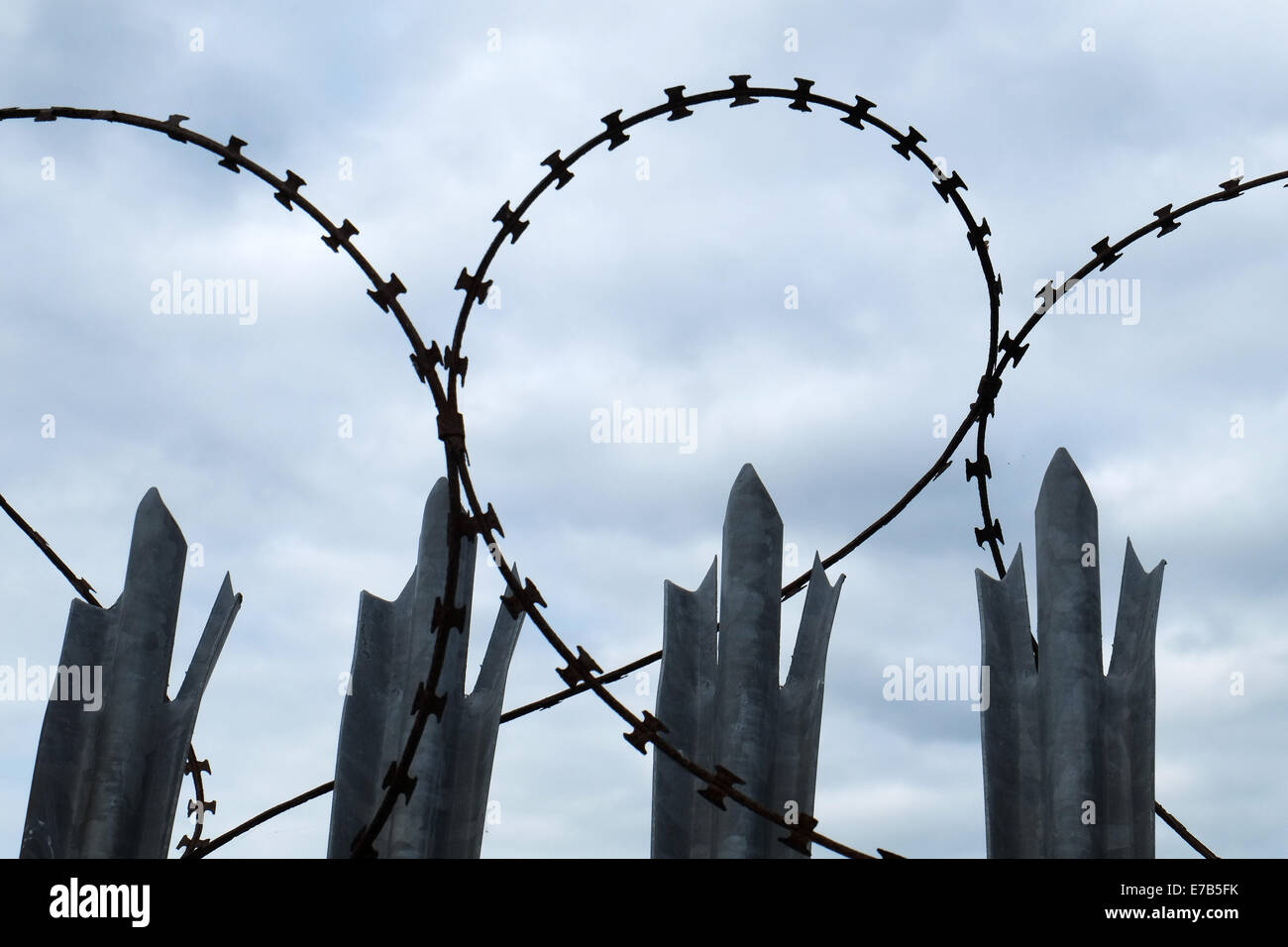 Razor wire and spiked steel posts. Stock Photo