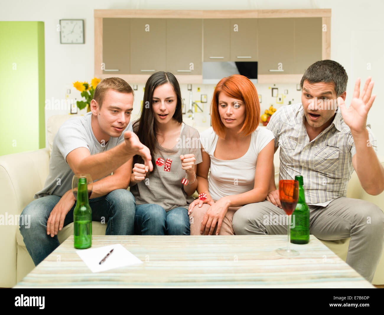 friends sitting on sofa, playing game with dices and having fun Stock Photo