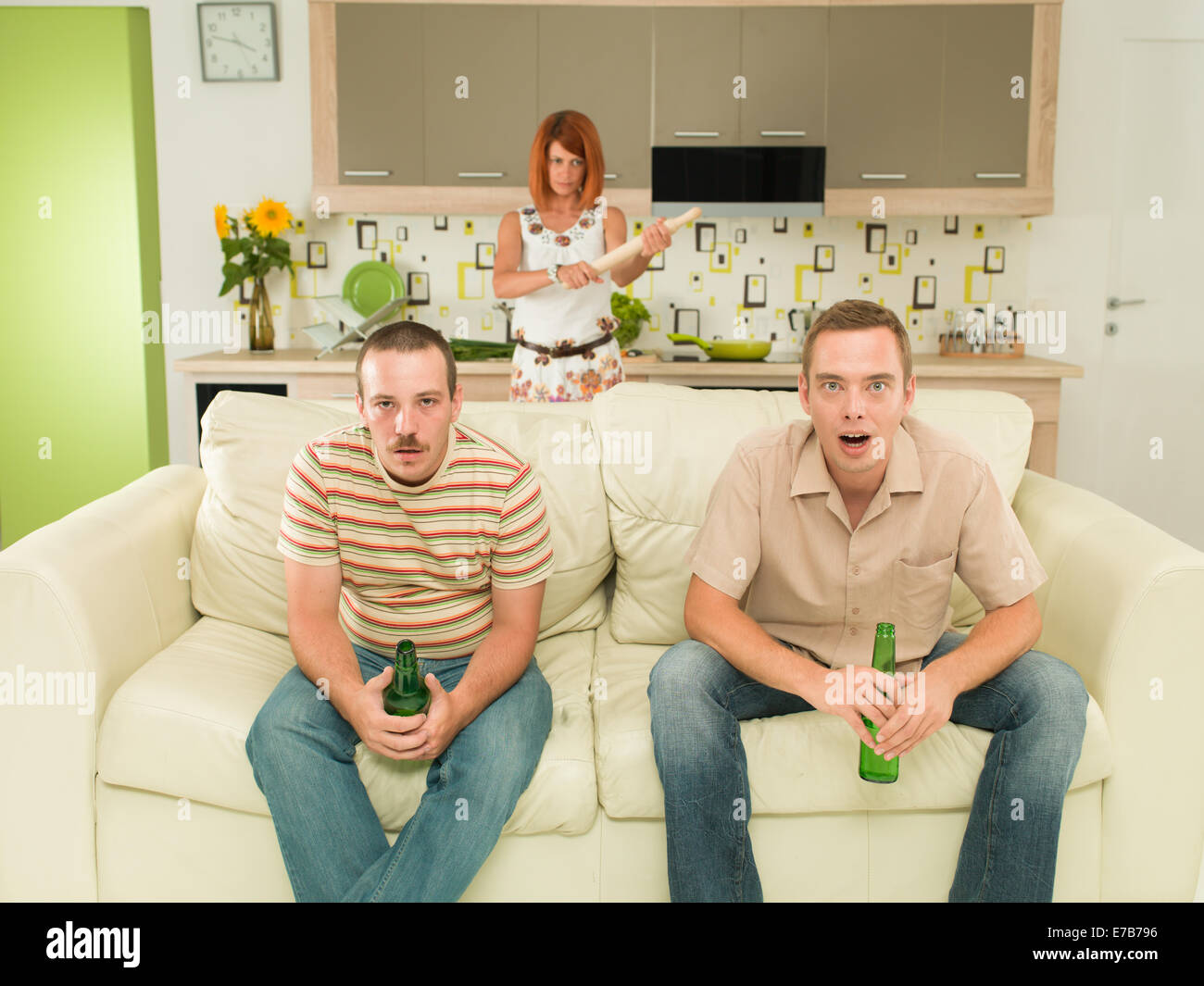 Two Men Sitting On Couch Watching Television In Kitchen Holding