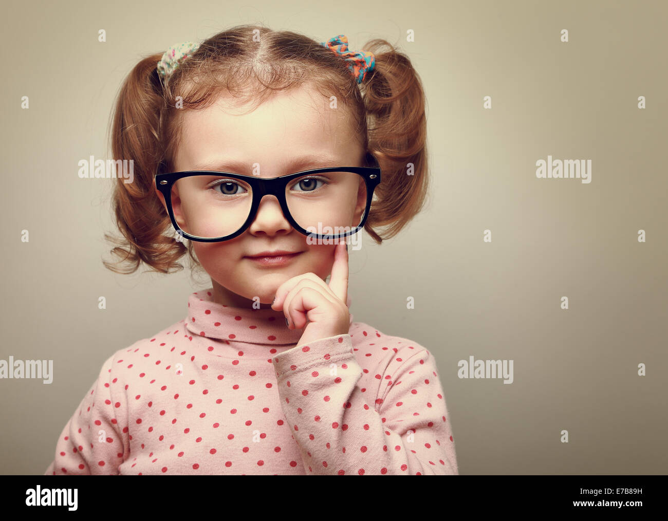 Thinking little kid girl looking happy in glasses. Vintage portrait Stock Photo