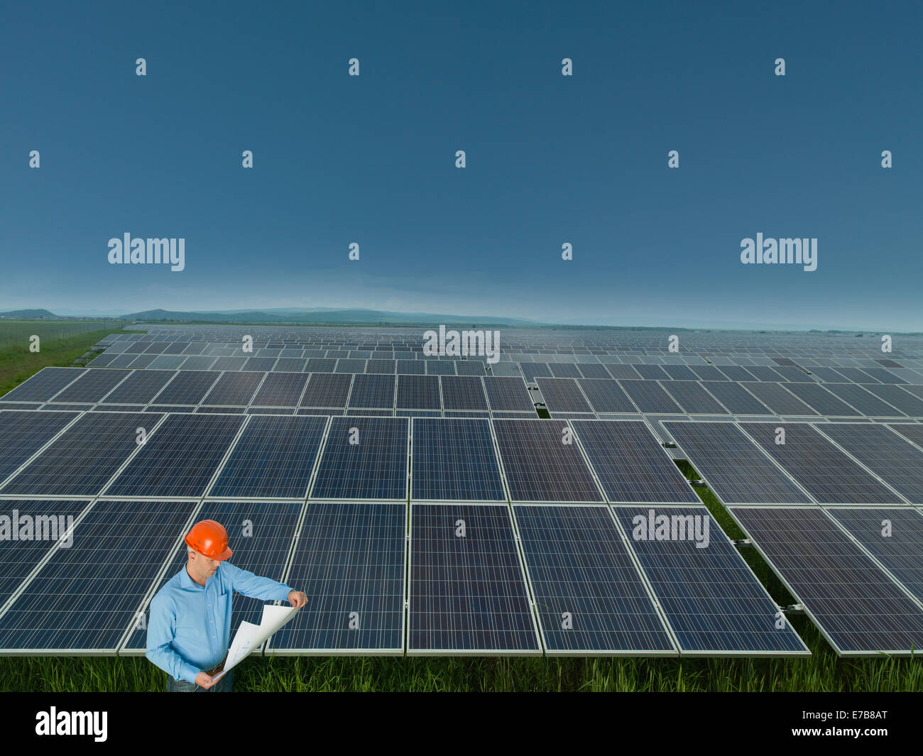 male engineer standing and reading blueprints in solar power station Stock Photo